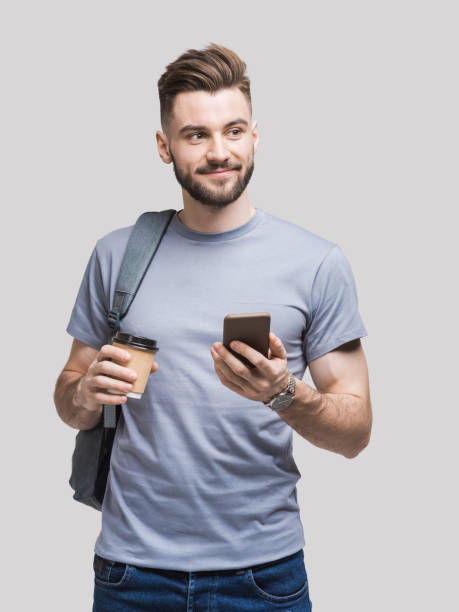 homem novo considerável de sorriso usando o smartphone - isolated cheerful businessman smiling - fotografias e filmes do acervo