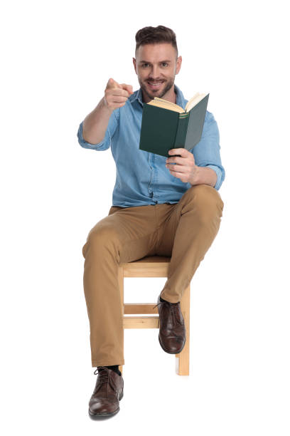 istock young casual man holding book and pointing finger 1200696630
