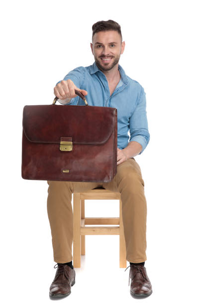 istock young casual man smiling and holding suitcase 1200696752