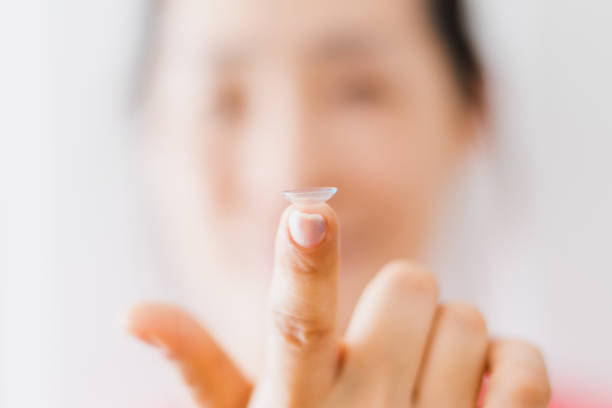 hermosa mujer poniendo lentes de ojos con las manos - insertar fotografías e imágenes de stock