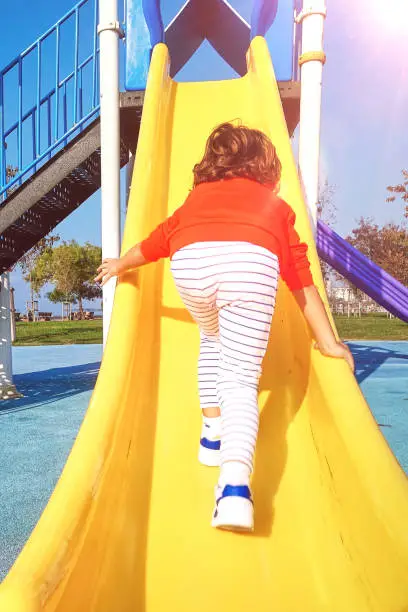 Photo of Excited little boy sliding down a slide