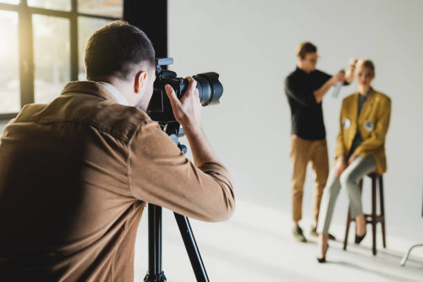 focus selettivo del fotografo che scatta foto di modello e parrucchiere - servizio fotografico foto e immagini stock