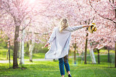 Tanzen, Laufen und Wirbeln in schönem Park mit Kirschbäumen in voller Blüte