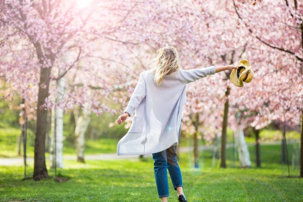 Dancing, running and whirling in beautiful park with cherry trees in bloom Young woman enjoying the nature in spring. Dancing, running and whirling in beautiful park with cherry trees in bloom. Happiness concept cherry blossom blossom tree spring stock pictures, royalty-free photos & images