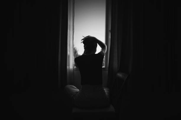 femme de déprime s'asseyant sur la présidence dans la salle près de la fenêtre dans le ton blanc, la tristesse et le concept de déprime - sexual violence photos et images de collection