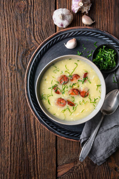 Caldo Verde soup made of savoy cabbage, pureed potatoes, onion, garlic and fried sausage slices in a ceramic bowl Caldo Verde soup made of savoy cabbage, pureed potatoes, onion, garlic and fried sausage slices in a ceramic bowl on rustic wooden background hot mix plant stock pictures, royalty-free photos & images