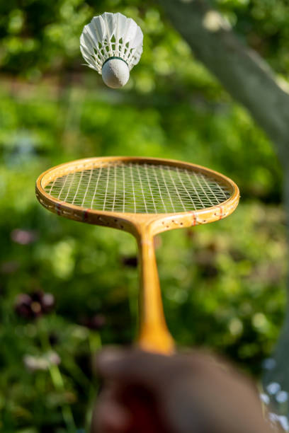 istock A hand is holding a badminton racket and tossing a shuttlecock, on a blurred green background, on a summer day. 1200705276