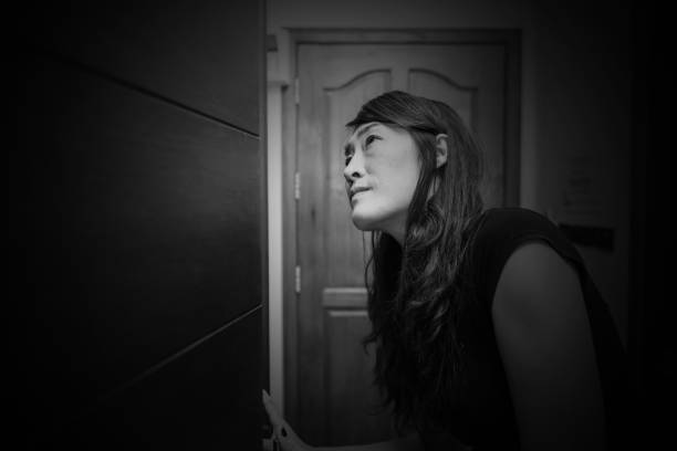 istock Scared woman looking on closet searching for something wrong in white tone 1200705331