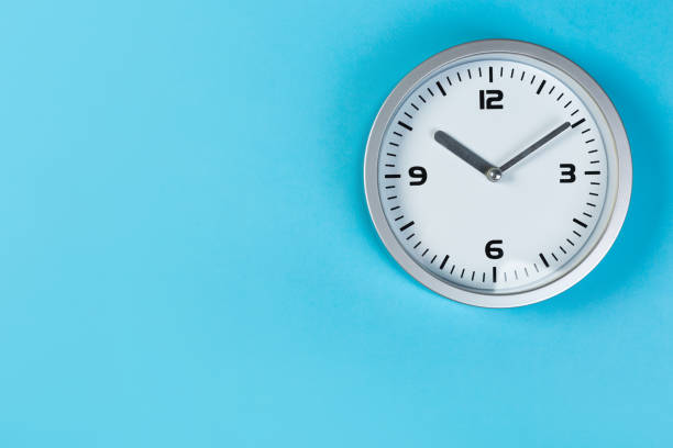 istock minimalistic white wall clock with light metal on a blue background. time concept. 1200705370
