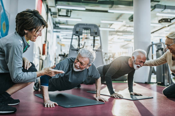 istock Senior men exercising push-ups in a gym while their wives are counting them. 1200705696