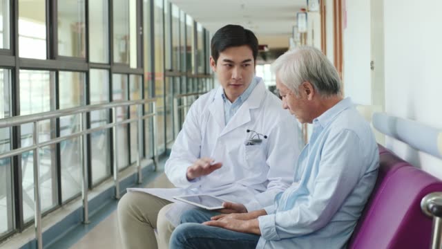 young asian doctor talking to senior asian patient