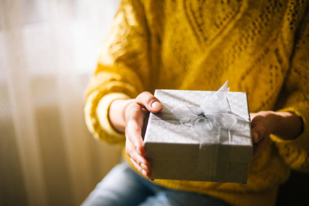 istock Young woman in yellow sweater holding gift box 1200706863