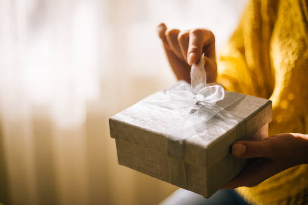 istock Young woman in yellow sweater opening gift box 1200706943