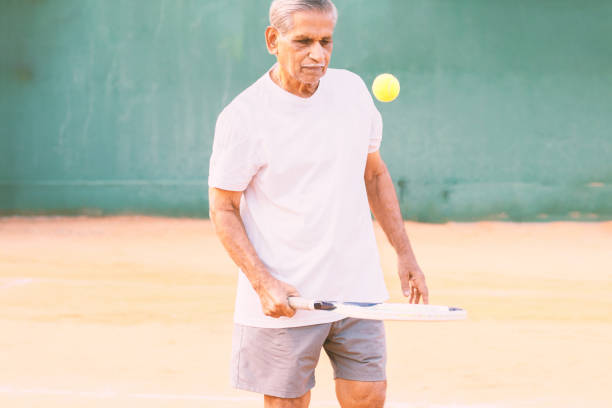 älterer mann spielt tennis - konzept der gesunden und fitten alten menschen - senior spieler üben tennis. - tennis active seniors healthy lifestyle senior men stock-fotos und bilder