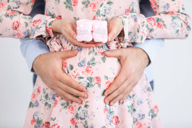 joven embarazada sosteniendo botines de bebé - gender reveal - it's a girl ! - party newborn baby hospital fotografías e imágenes de stock