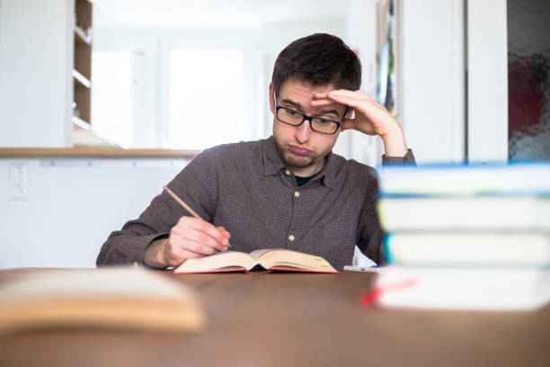 apprendre et étudier le concept : jeune étudiant d'échappement et étudiant masculin malheureux apprend à la maison, pile de livres - overstrained photos et images de collection