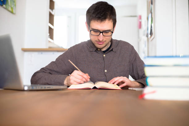 istock Learning and studying concept: Young happy male student is learning at home, stack of books 1200713849