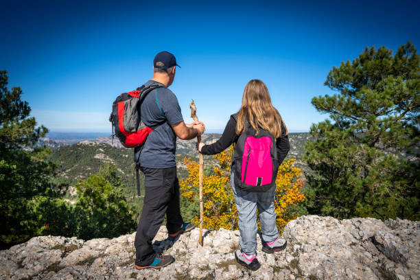 Trekking father and daughter on autumn mountain tip
