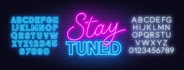 Neon sign stay tuned on brick wall background. Neon sign stay tuned on brick wall background . Neon alphabet on a dark background. stay tuned concept stock illustrations