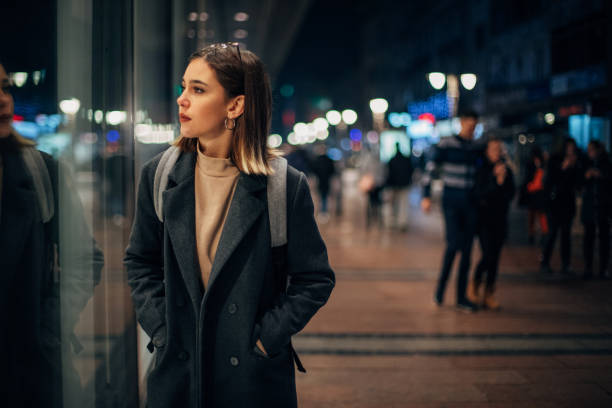 Young woman looking to store window Beautiful young woman standing on the street and looking to store window window shopping at night stock pictures, royalty-free photos & images