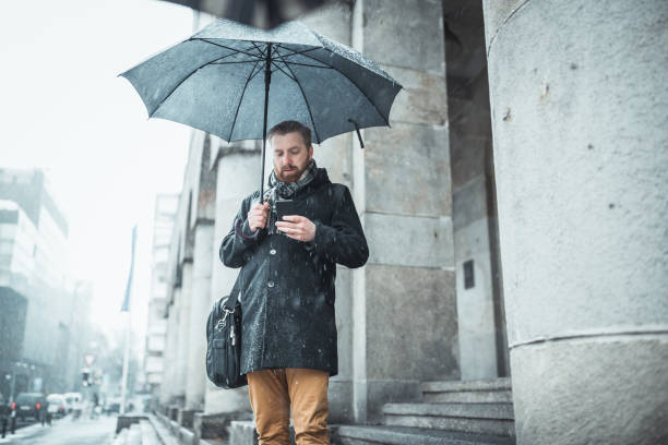 istock Ginger businessman standing on office building entrance, using a mobile phone 1200719769