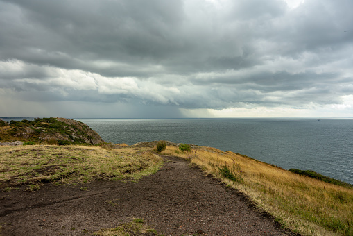 Storm entering from the sea at the south coast of Sweden, with dark overcast sky and a distant rain falling leaving traces in the air