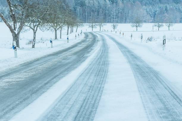 tráfego solitário de estrada de inverno gelada com pista branca de neve - car winter road reflector snow - fotografias e filmes do acervo