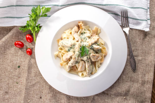 istock fettuccine pasta with chicken and cheese sauce on white plate on tablecloth 1200721195
