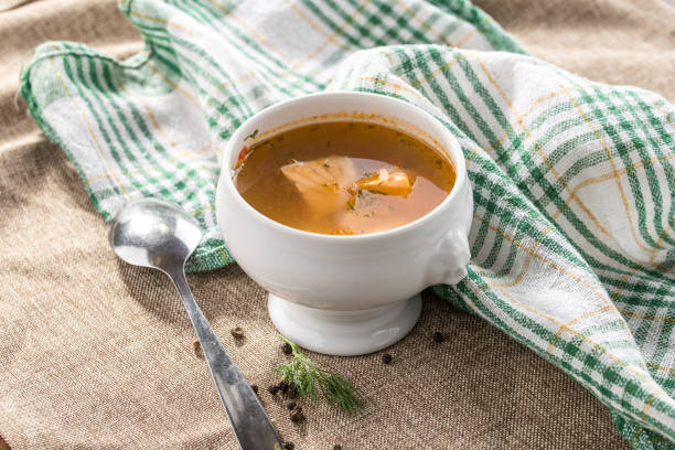 istock Fresh fish soup with spices in white bowl and spoon on grey tablecloth 1200721240