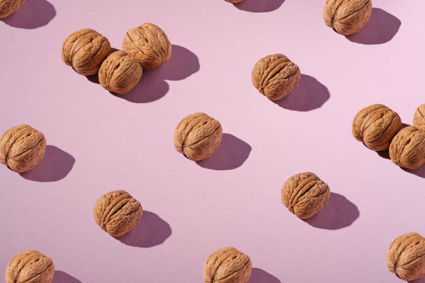 istock Walnuts with shell in row composition, minimalist abstract design pattern, healthy food, angle view, pink background 1200721260