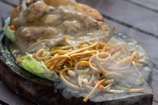 A steaming chicken sizzler on a hot plate.