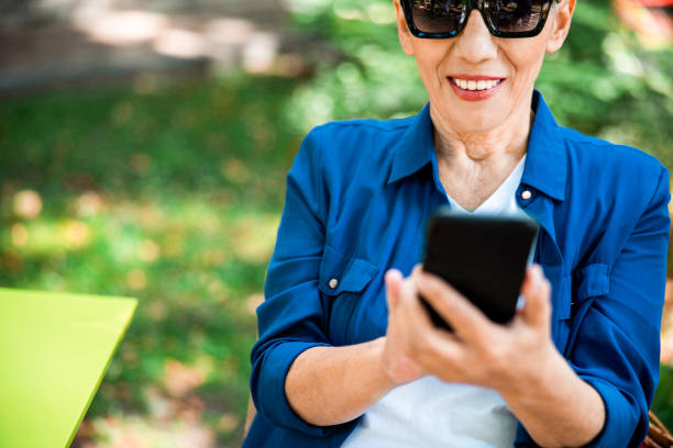 istock Cheerful mature lady using smartphone on the street 1200723829