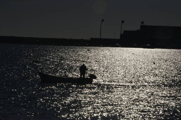 Silhouette of a man in a boat, at sea at sunset