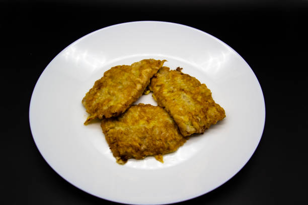 istock White plate with chops with meat on a black background. Fried meat in an egg on a plate. Three fried chops 1200727505