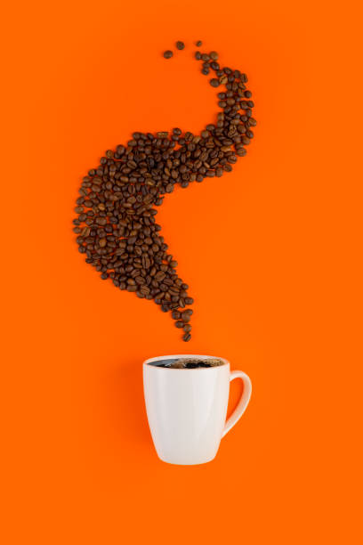 istock Coffee in a white cup on an orange background with coffee beans. 1200728625