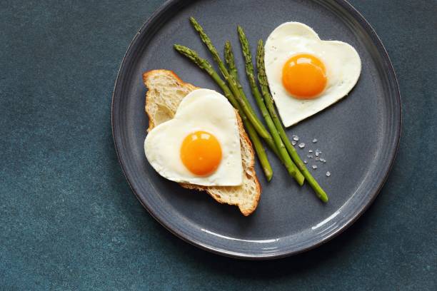 istock Fried eggs in the shape of a heart  on blue plate. 1200728682