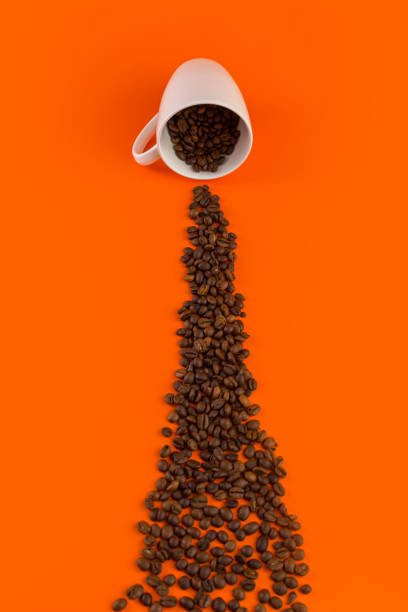 istock Coffee in a white cup on an orange background with coffee beans. 1200728694