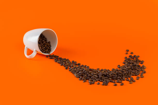istock Coffee in a white cup on an orange background with coffee beans. 1200728731