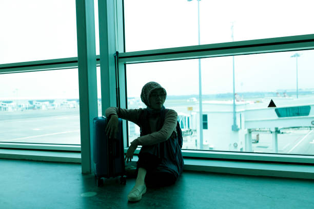 istock a woman with baggage sitting in airport floor 1200728749