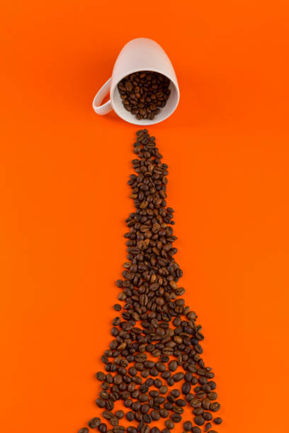 istock Coffee in a white cup on an orange background with coffee beans. 1200728755