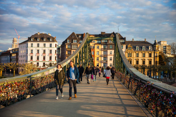 Frankfurt am Main, Germany- April 18, 2016: People walking in Iron Bridge. Frankfurt am Main city. The Iron Footbridge was erected in 1868-69 by a private company of citizens as a third bridge across the Main connecting the center of Frankfurt with Sachsenhausen.