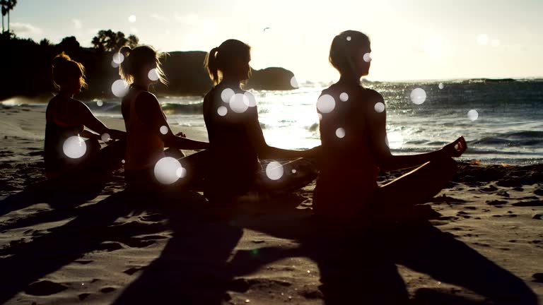 Rear view of women mediating on sand