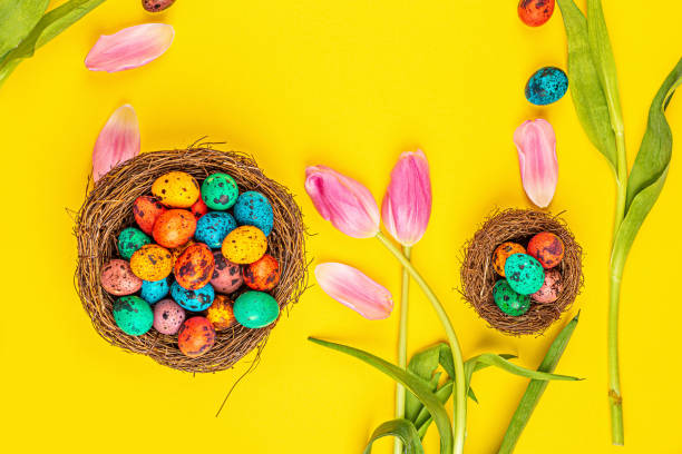 istock Stylish background with colorful easter eggs isolated on yellow background with pink tulip flowers. Flat lay, top view, mockup, overhead, template 1200730651