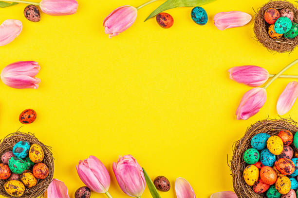 istock Stylish background with colorful easter eggs isolated on yellow background with pink tulip flowers. Flat lay, top view, mockup, overhead, template 1200730850