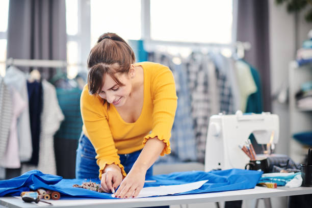 istock Creative caucasian fashion designer standing in her studio and drawing scheme on blue linen for a beautiful evening dress. 1200732620
