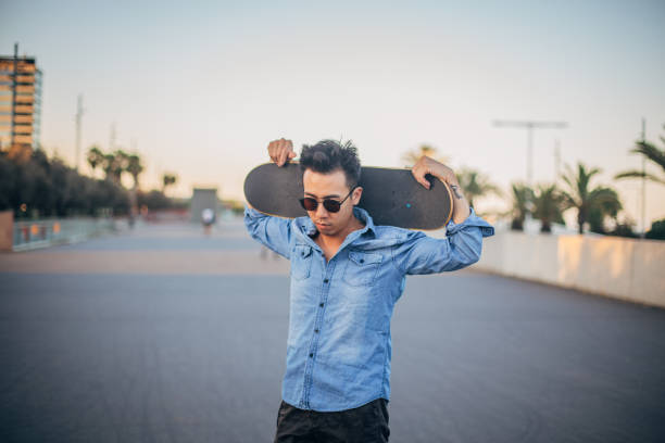 istock Man with skateboard walking on the street 1200732865