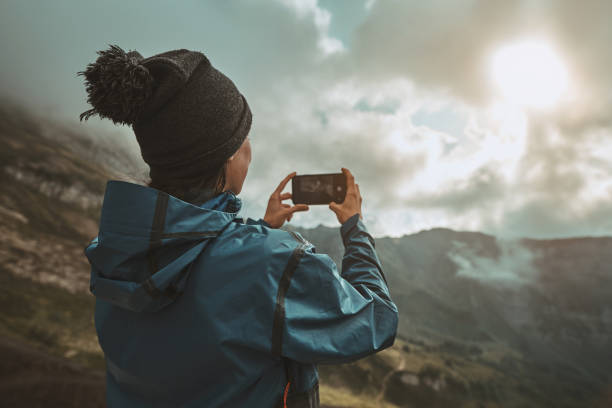 A hiker girl take a pictures on a smartphone in the mountains stock photo