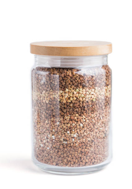 istock glass jar with buckwheat poured in layers isolated on white background. side view, close up. Healthy food concept. 1200734254