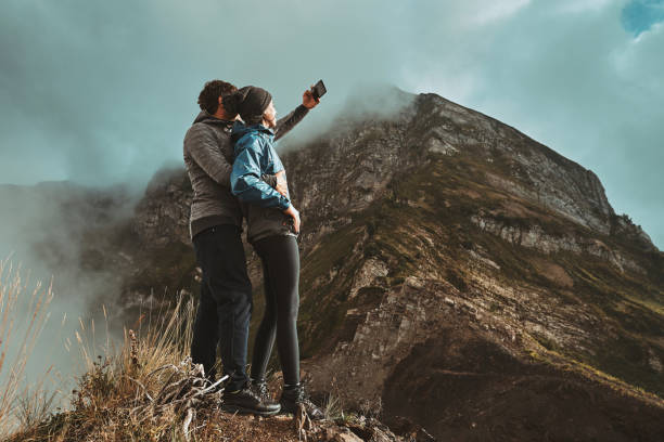 a young couple hugges on a cliff and takes a selfi photo stock photo