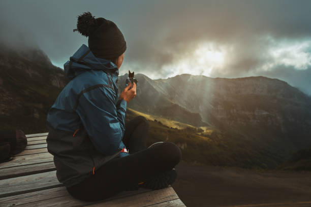 A hiker girl sits on the viewpoint and eats an energy bar stock photo